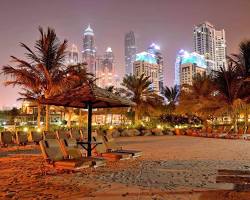 منظر بانورامي لشاطئ جميرا الليلي في دبي مع إضاءة الممشى وانعكاس الأضواء على البحر