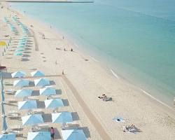 لقطة لشاطئ مفتوح في دبي تظهر ممرات المشي والمرافق العامة المجهزة للزوار تحت أشعة الشمس.