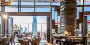 صورة لمطعم فاخر في دبي يطل على أفق المدينة وبرج خليفة مع جداول وترتيبات.